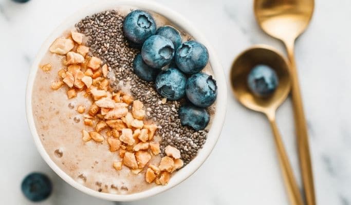 smoothie bowl topped with seeds, blueberries, and nuts