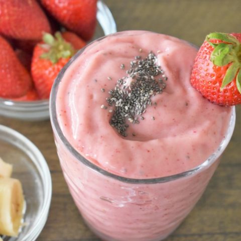 strawberry chia smoothie in a glass with strawberries and bananas off to the side