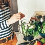 woman adding smoothie ingredients to blender