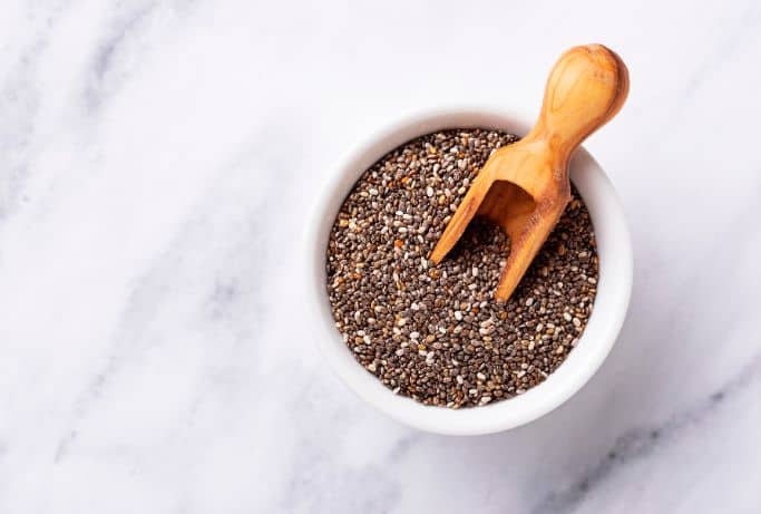 chia seeds in white bowl on marble background