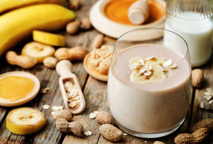 peanut butter smoothie surrounded by peanuts and bananas