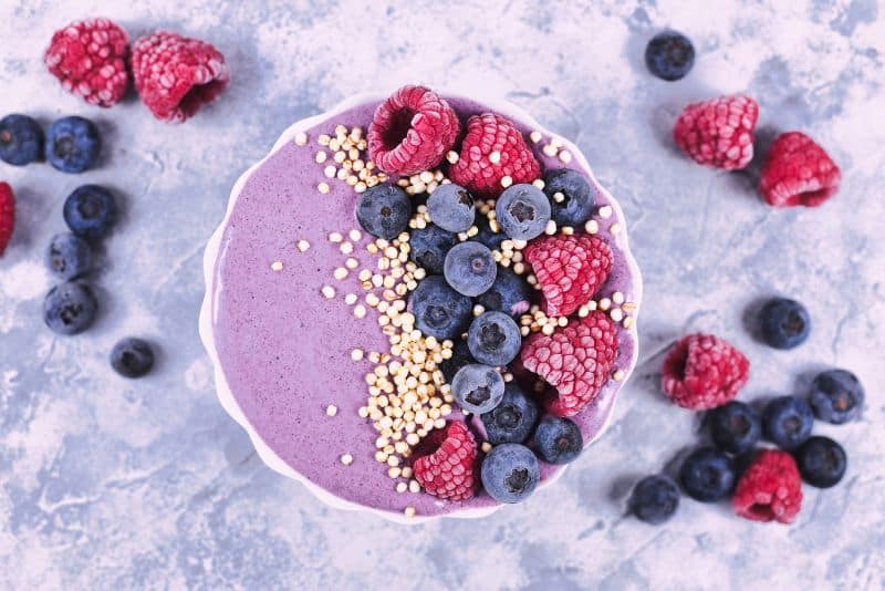 smoothie bowl topped with puffed quinoa, blueberries, and raspberries