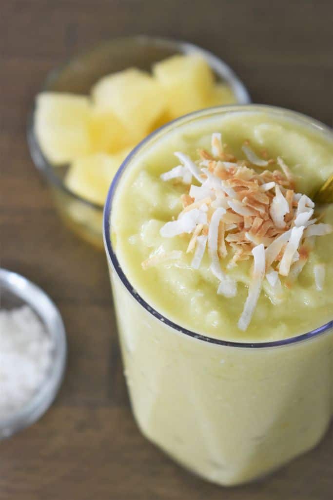 tall glass of avocado pineapple smoothie with coconut